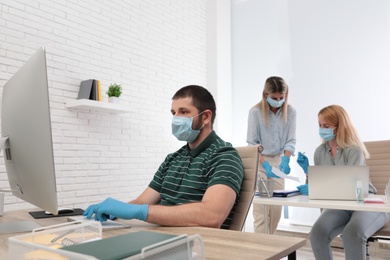 Photo of Office employees in masks and gloves at workplace