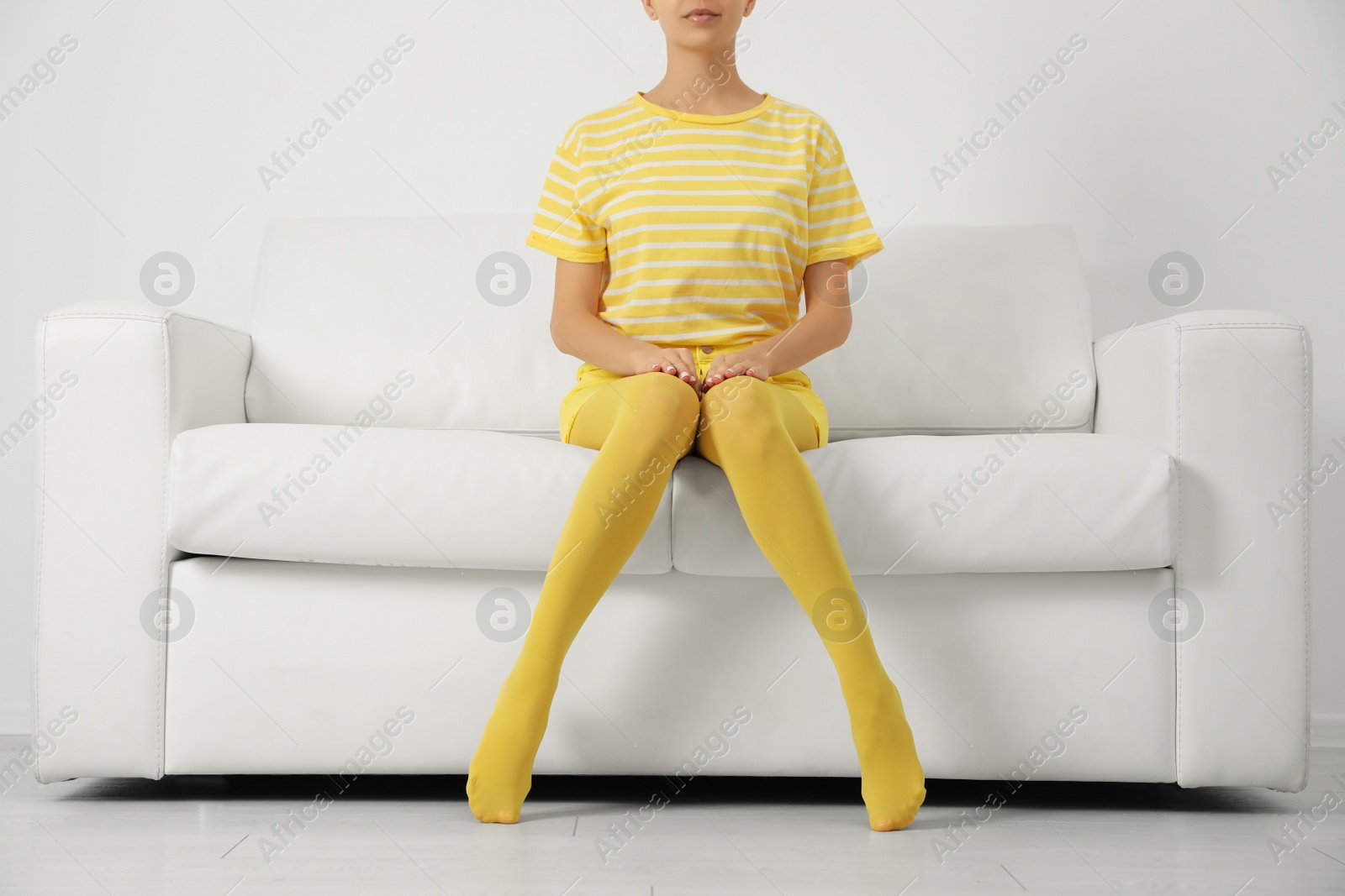 Photo of Woman wearing yellow tights sitting on sofa indoors, closeup