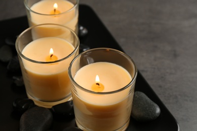 Photo of Dark plate with three burning candles on table. Space for text