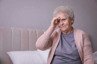 Photo of Senior woman with headache in bedroom at home. Space for text