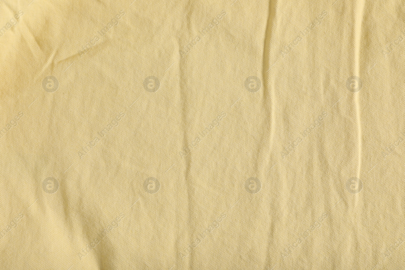 Photo of Crumpled pale yellow fabric as background, top view