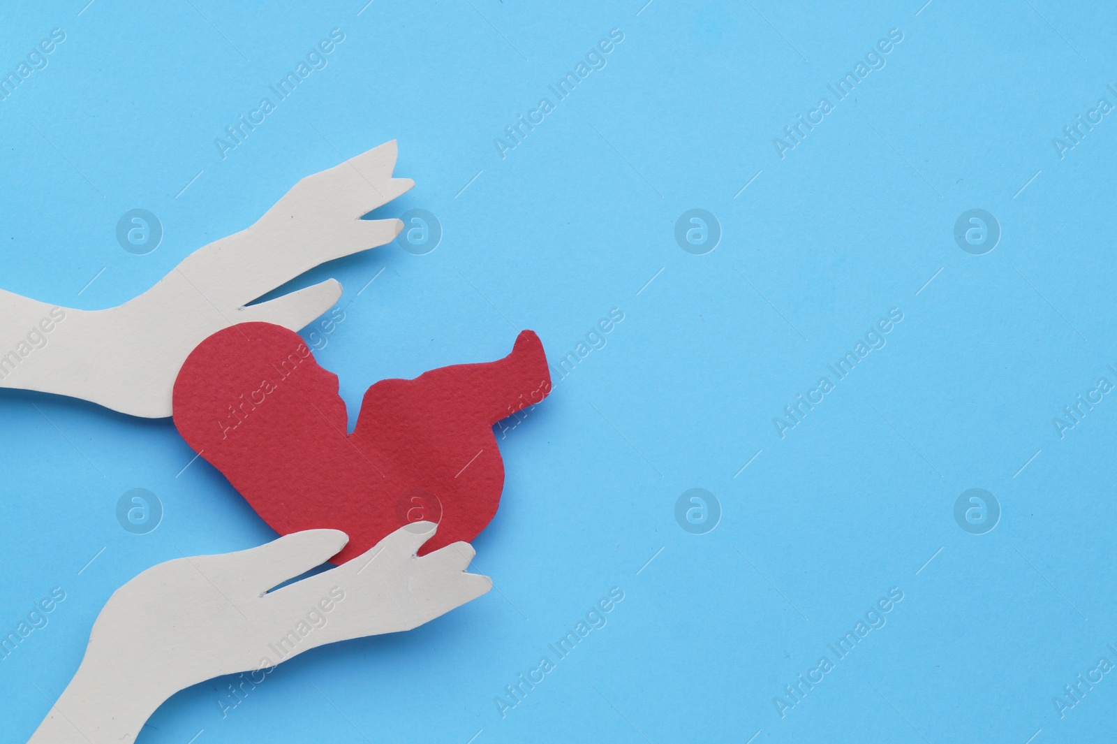 Photo of Woman`s health. Hands with newborn paper figure on light blue background, flat lay. Space for text