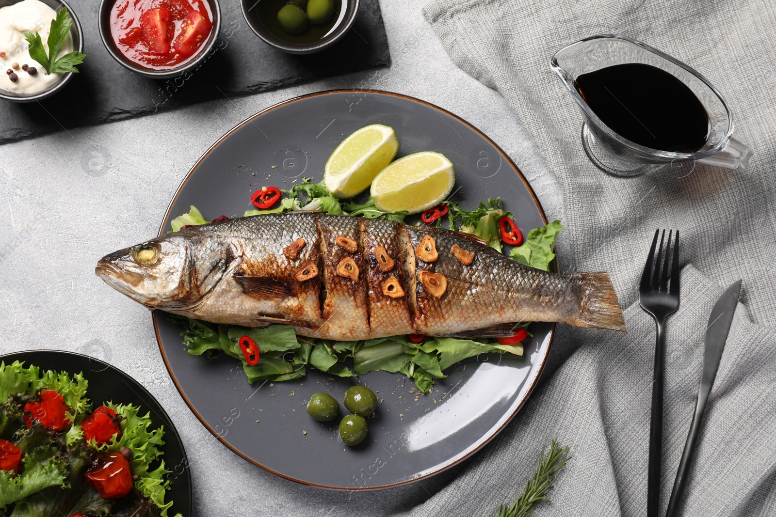 Photo of Flat lay composition with delicious sea bass fish, sauces and ingredients served on light grey table