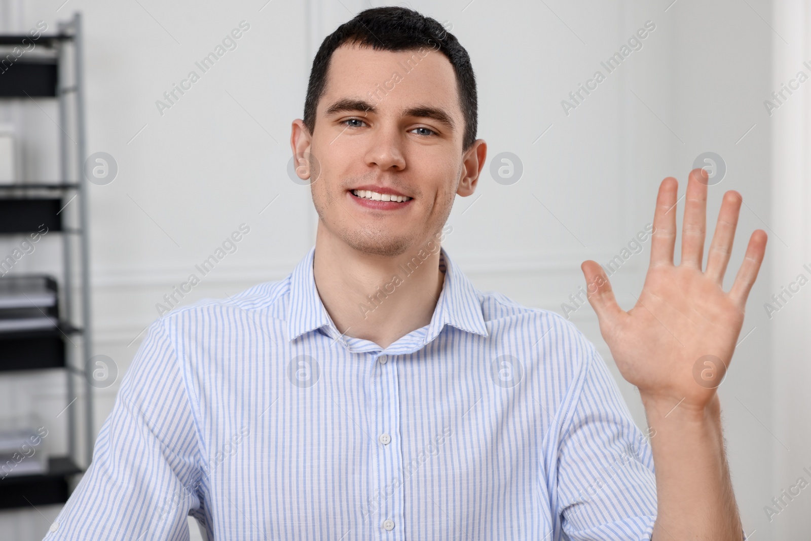 Photo of Man waving hello while having video chat in office, view from web camera
