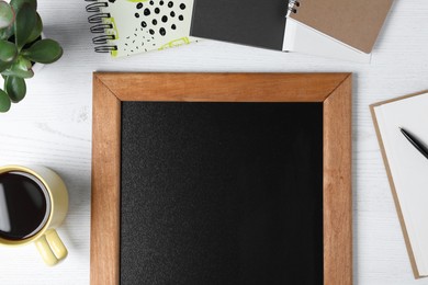 Photo of Clean small chalkboard, coffee, plant and stationery on white wooden table, flat lay