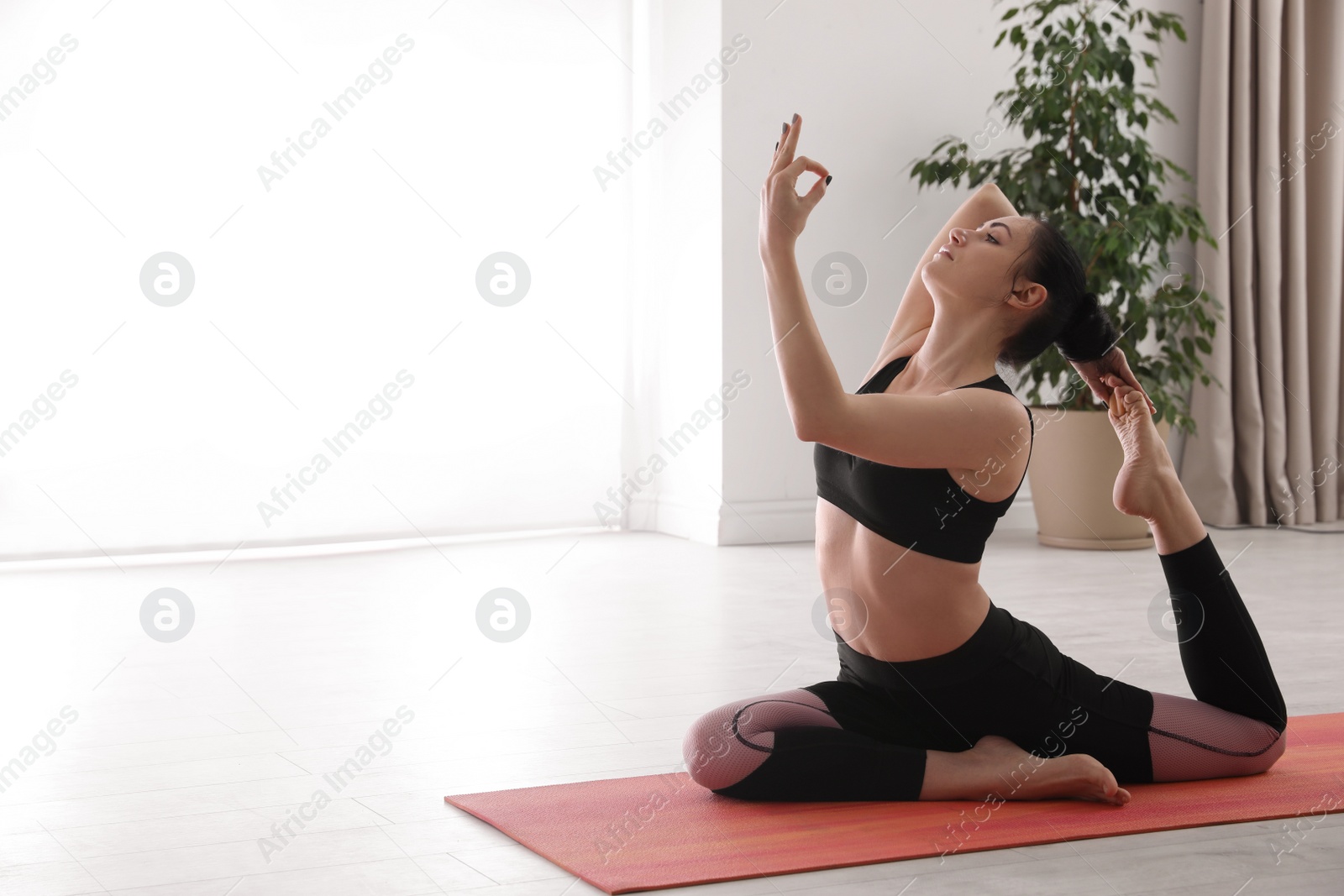 Photo of Woman practicing one legged king pigeon asana in yoga studio. Eka pada rajakapotasana pose