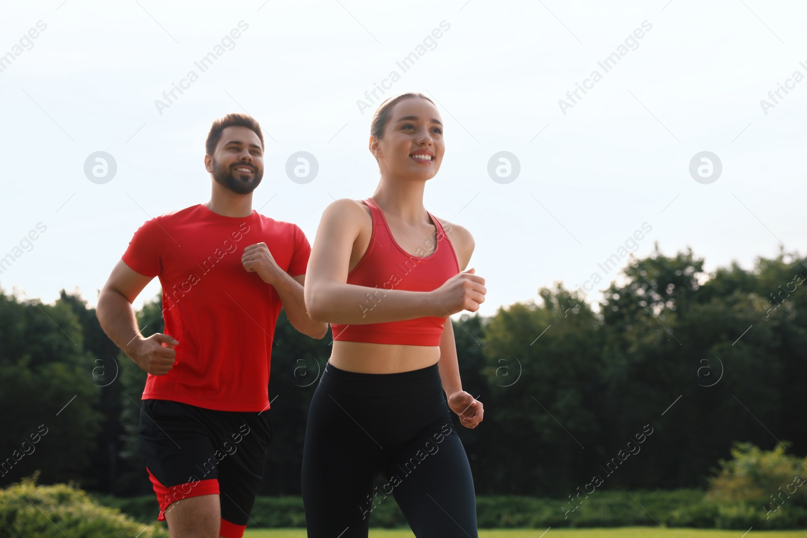 Photo of Healthy lifestyle. Happy couple running outdoors on sunny day. Space for text