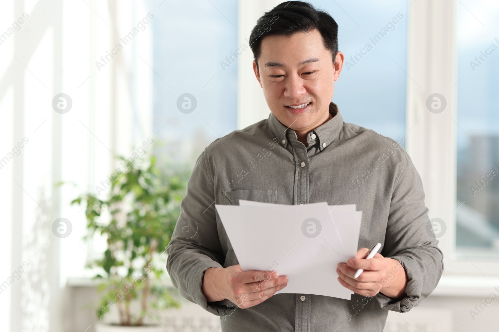 Photo of Portrait of smiling businessman with documents in office. Space for text