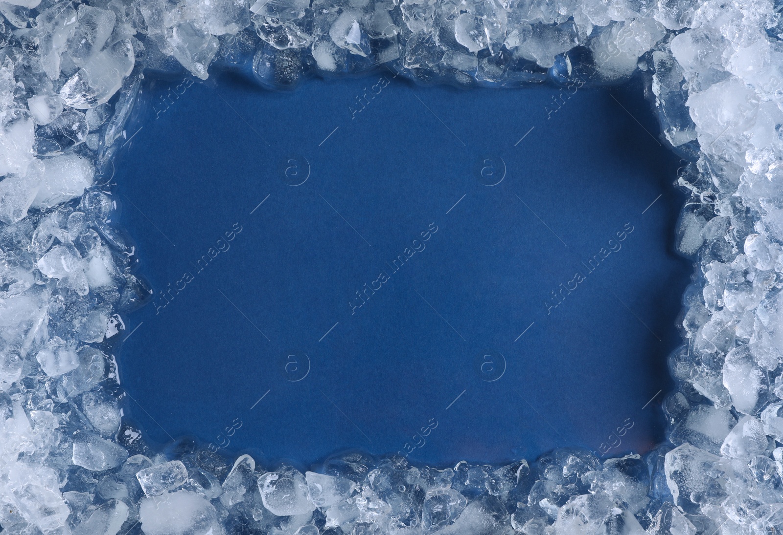 Photo of Frame of crushed ice on blue background, top view. Space for text