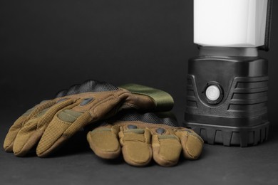 Photo of Tactical gloves and camping lantern on black background. Military training equipment