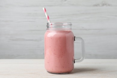 Photo of Mason jar with delicious berry smoothie on white wooden table