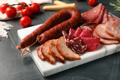 Photo of Cutting board with different sliced meat products served on table