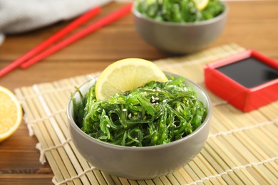 Photo of Japanese seaweed salad with lemon slice served on table, closeup