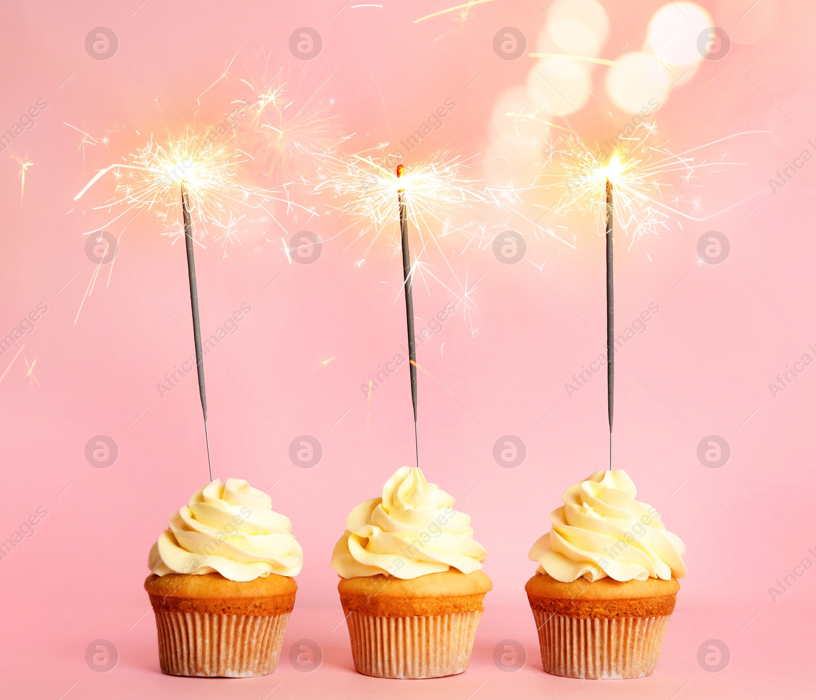 Image of Birthday cupcakes with sparklers on pink background