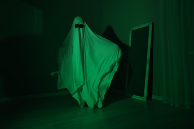 Creepy ghost. Woman covered with sheet in green light