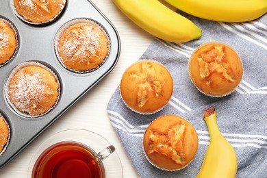 Photo of Flat lay composition with homemade banana muffins and tea on white wooden table