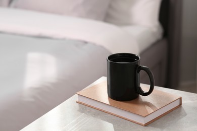 Black ceramic mug and book on table indoors. Mockup for design