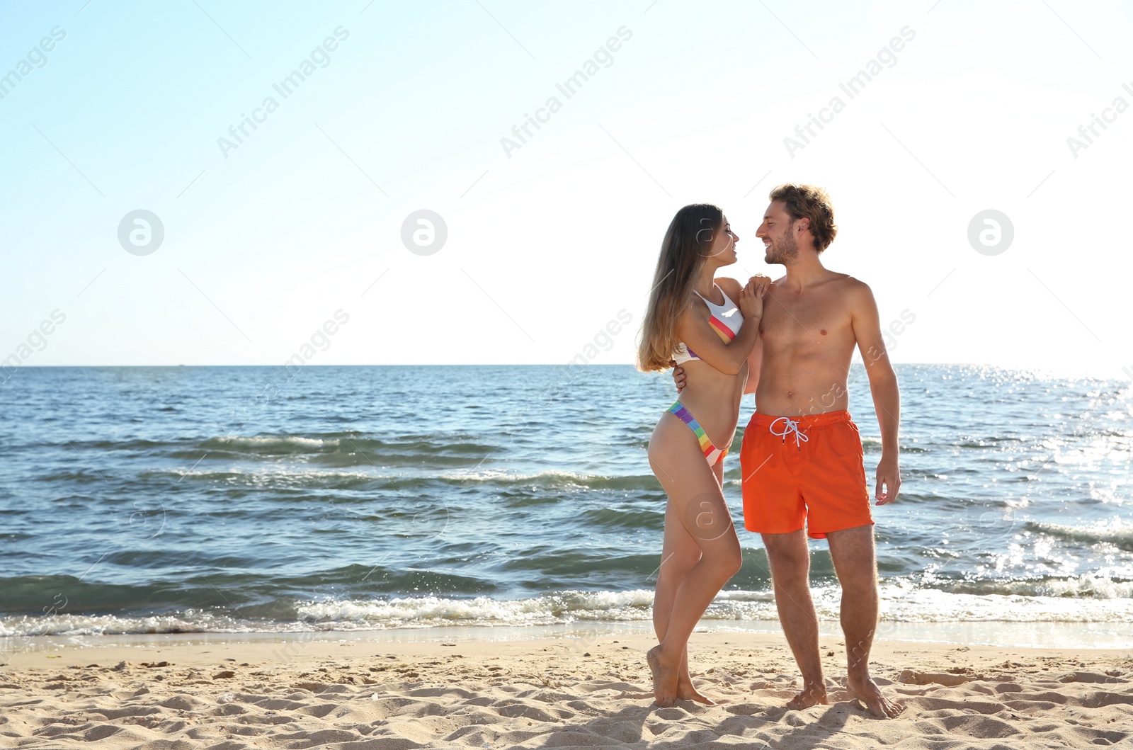 Photo of Happy young couple in beachwear posing on seashore