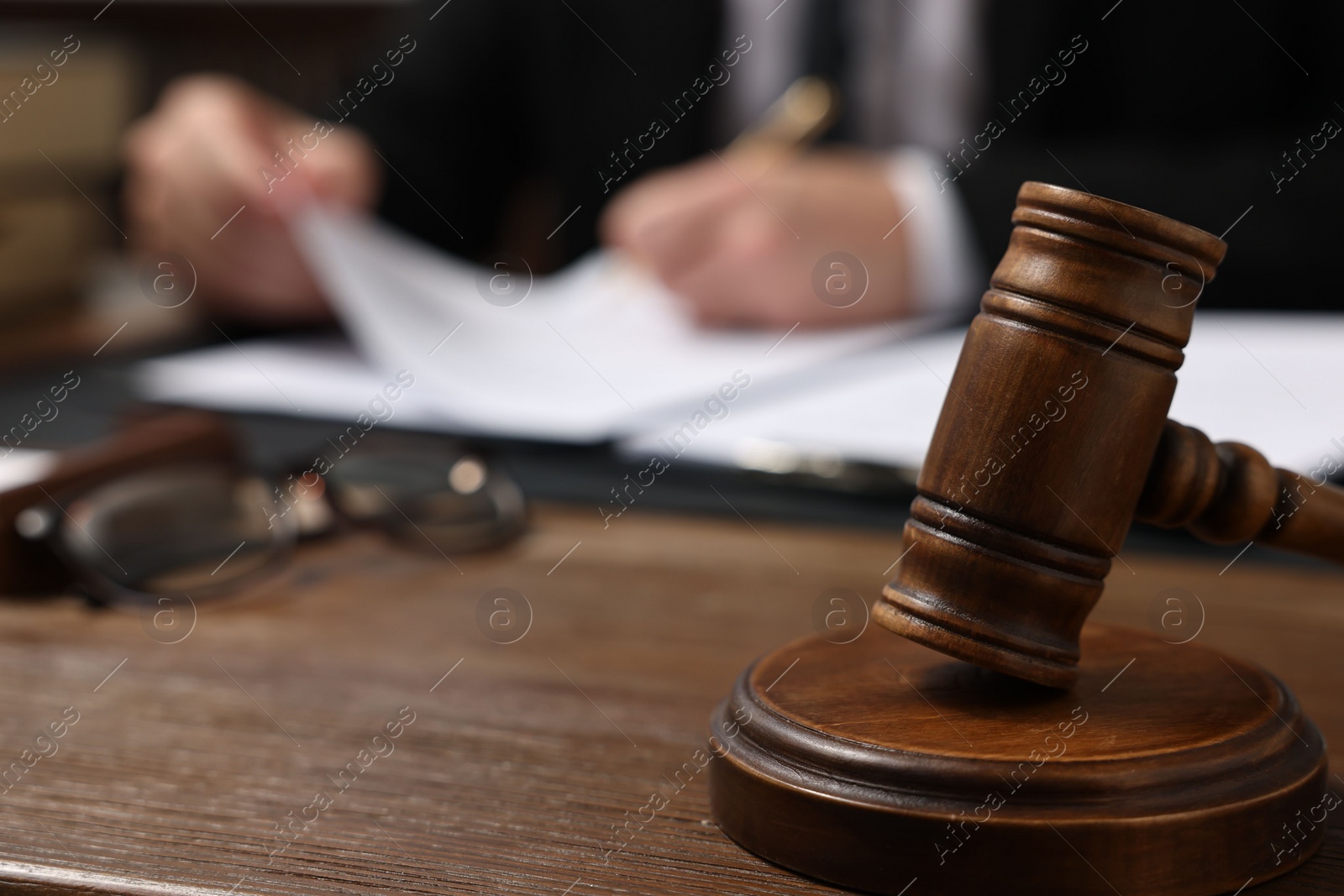 Photo of Lawyer working with documents at wooden table, focus on gavel