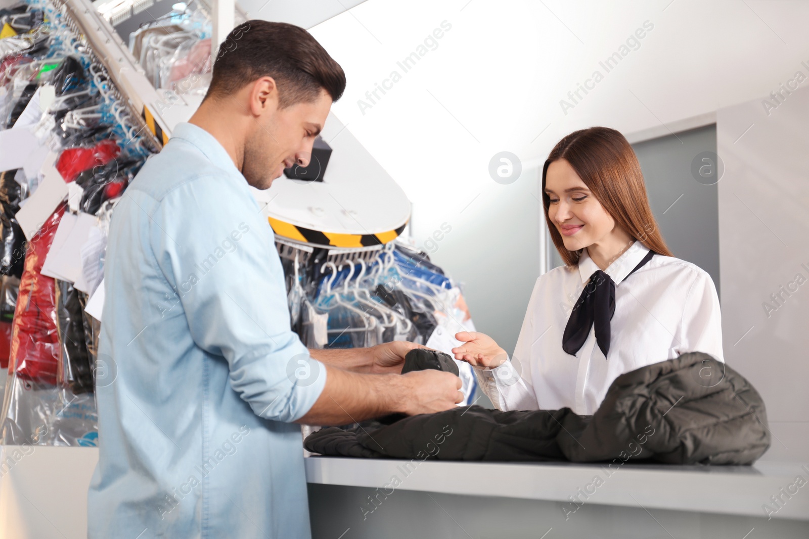 Photo of Client and worker with jacket at modern dry-cleaner's