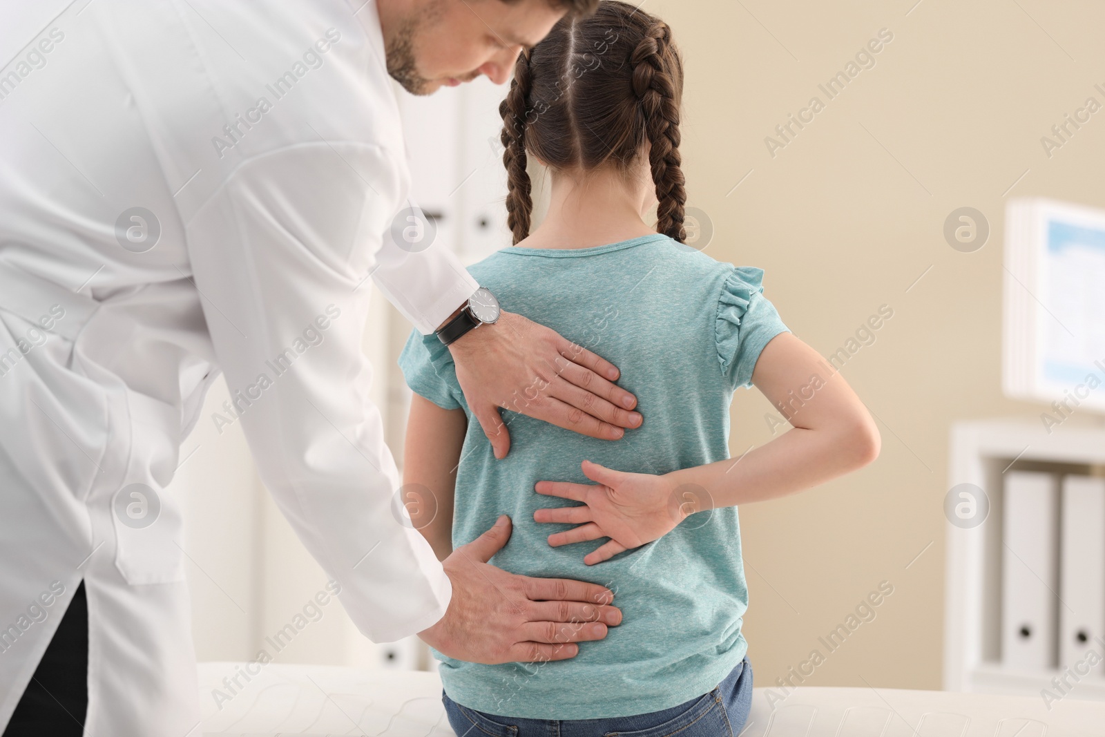 Photo of Chiropractor examining child with back pain in clinic