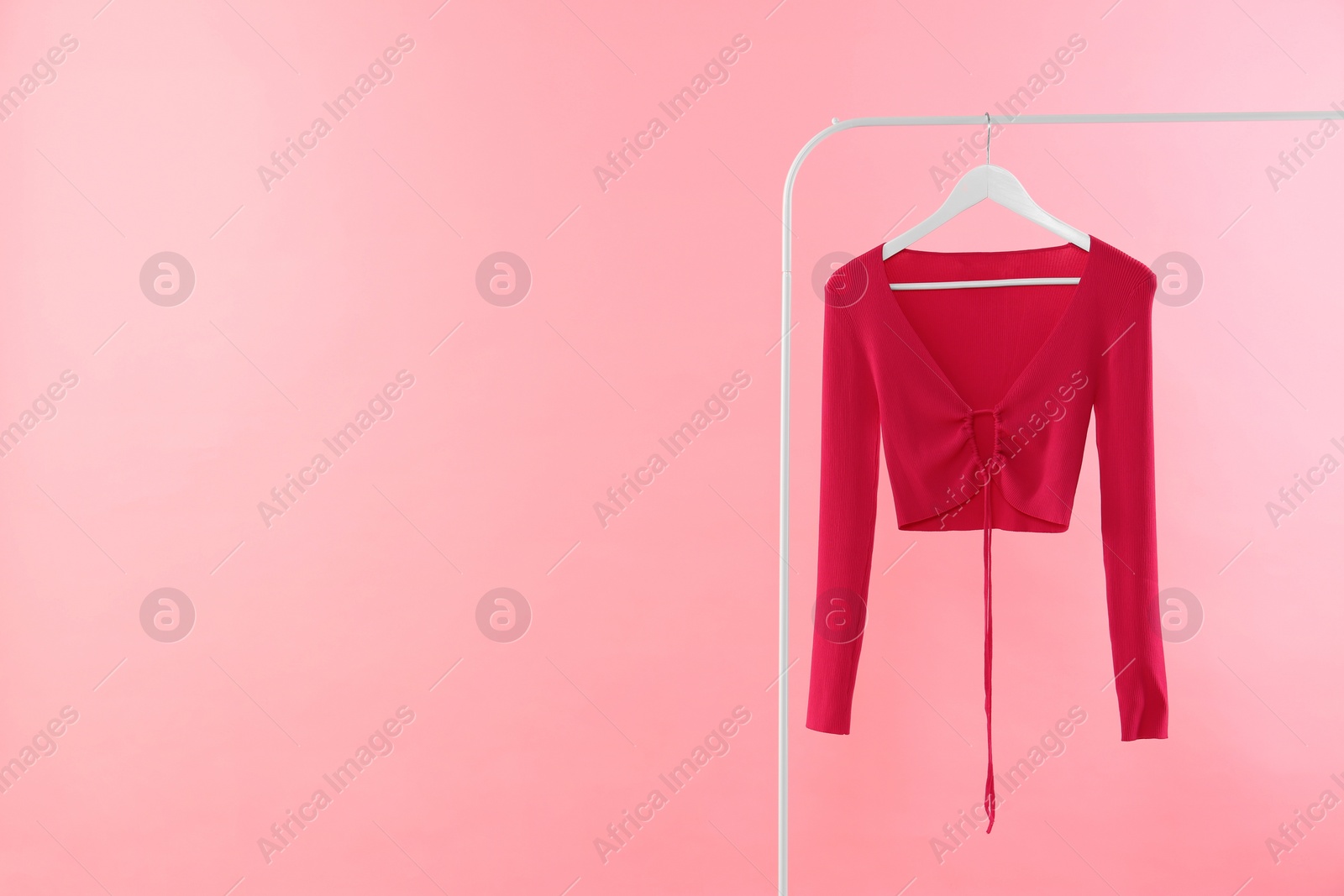 Photo of Rack with stylish woman's top on pink background. Space for text