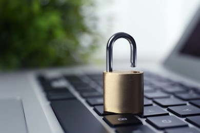 Photo of Metal padlock on laptop keyboard, space for text. Cyber security concept