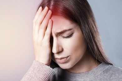Image of Young woman suffering from migraine on grey background