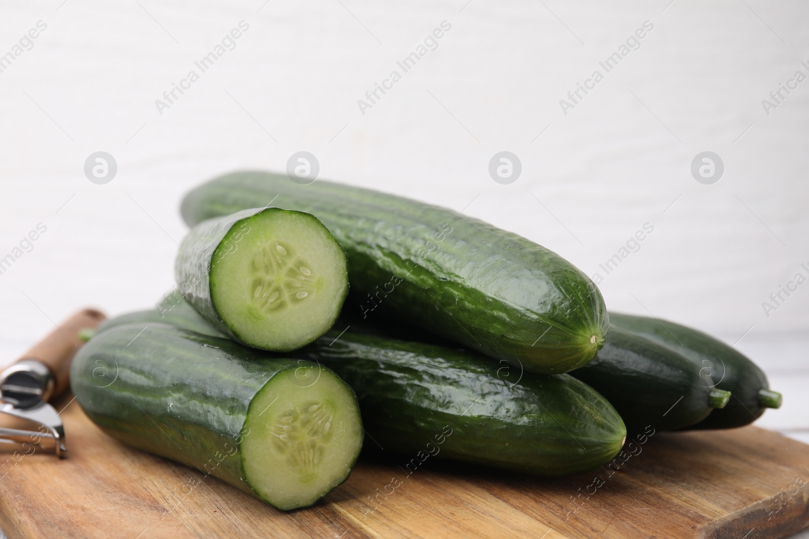 Photo of Many fresh cucumbers on wooden board, closeup