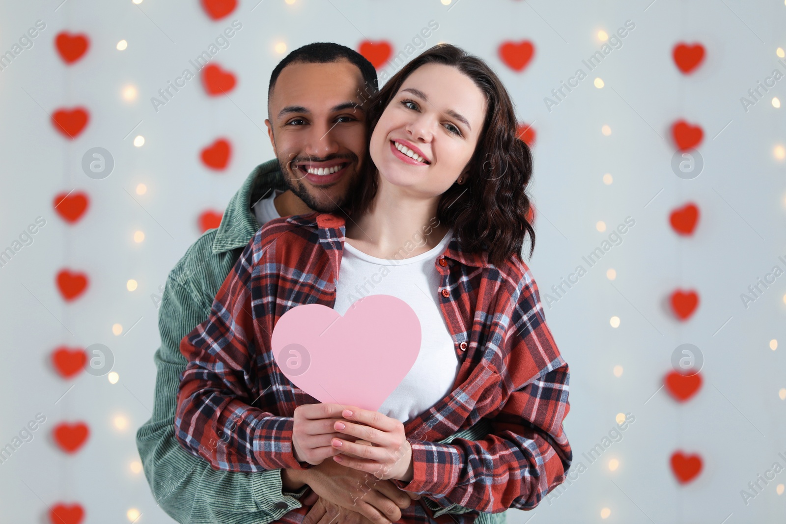 Photo of Lovely couple with pink paper heart indoors. Valentine's day celebration