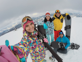 Group of friends with equipment taking selfie at ski resort. Winter vacation