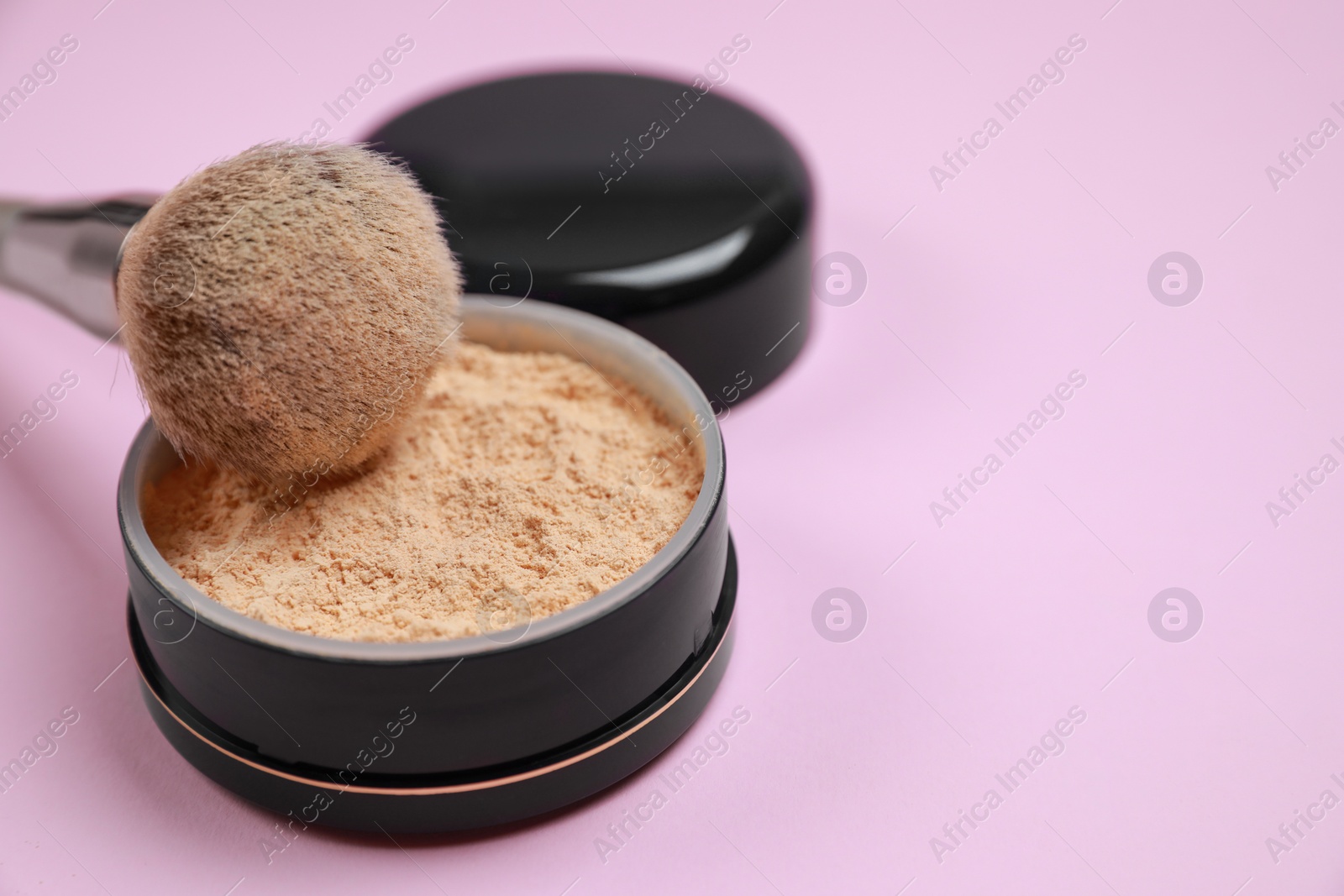 Photo of Face powder and brush on pink background, closeup. Space for text