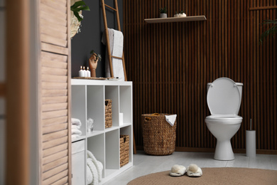 Photo of Elegant modern bathroom with toilet bowl near wooden wall