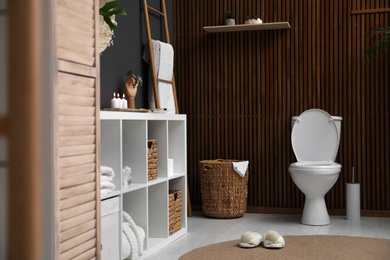 Elegant modern bathroom with toilet bowl near wooden wall