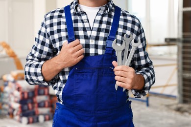 Photo of Professional builder in uniform with tools indoors, closeup
