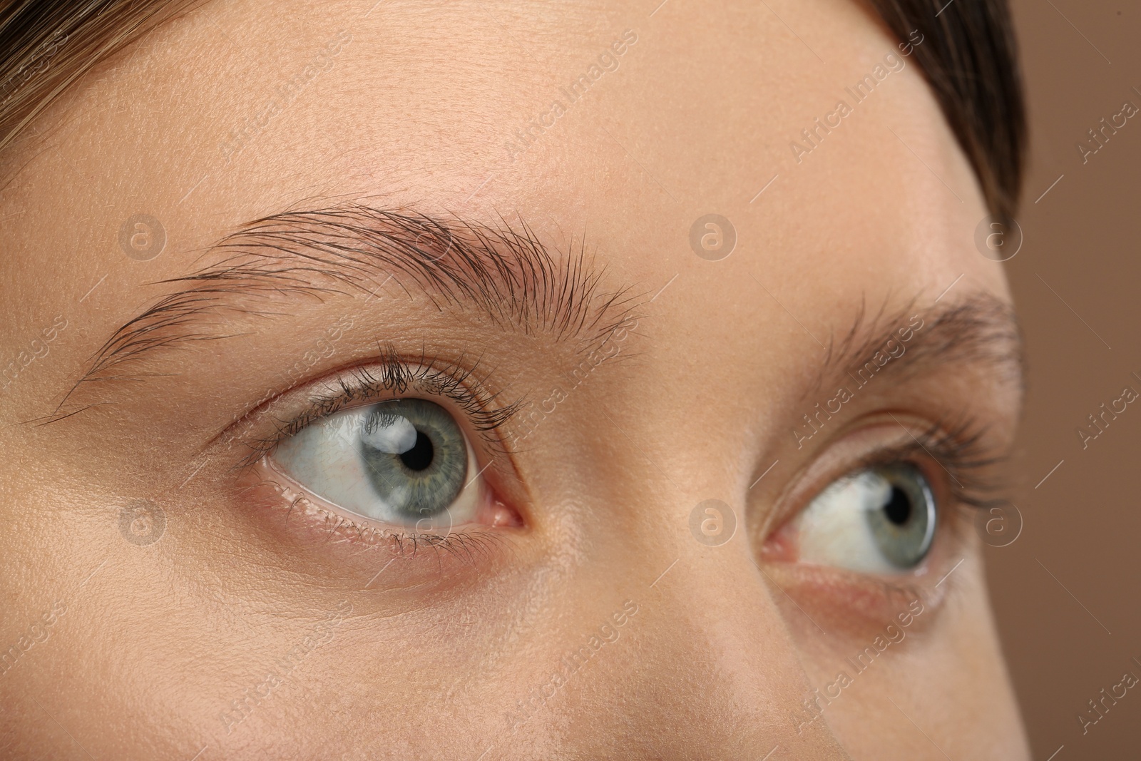 Photo of Woman with beautiful natural eyelashes on light brown background, closeup