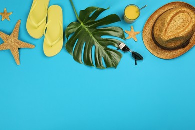 Flat lay composition with beach objects on light blue background, space for text