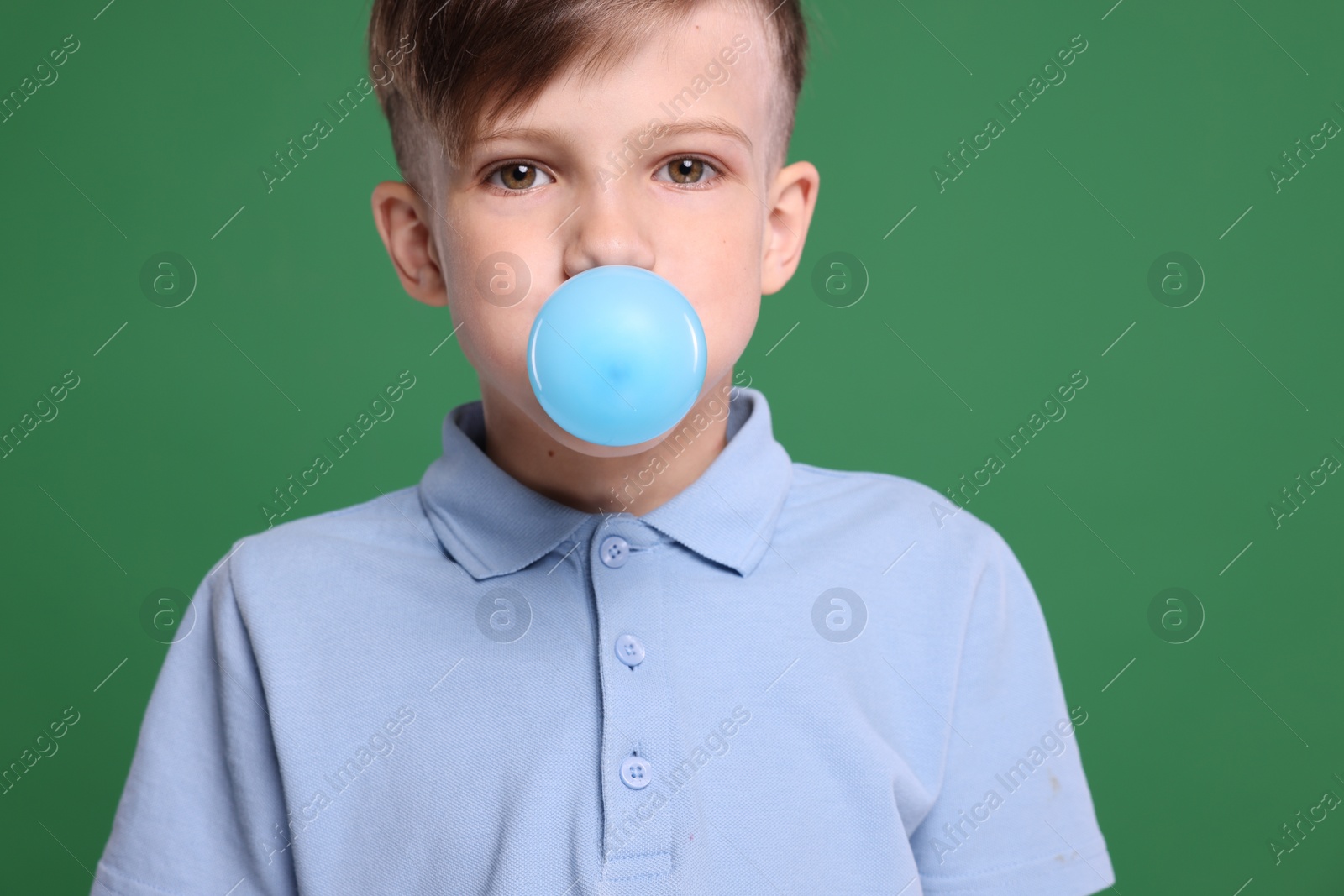 Photo of Boy blowing bubble gum on green background