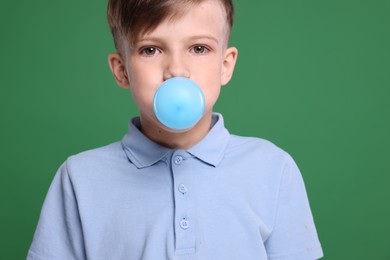 Photo of Boy blowing bubble gum on green background