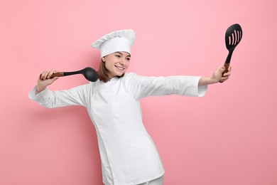 Photo of Professional chef with skimmer and ladle having fun on pink background