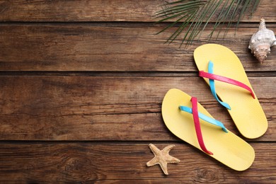 Photo of Stylish flip flops, seashell and starfish on wooden background, flat lay. Space for text