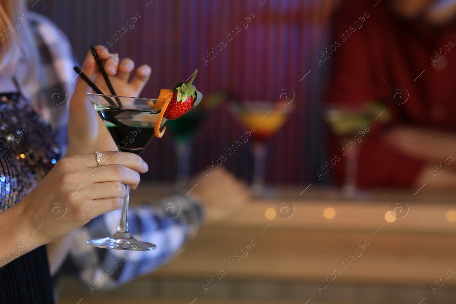 Photo of Young woman with glass of martini cocktail in bar, closeup. Space for text