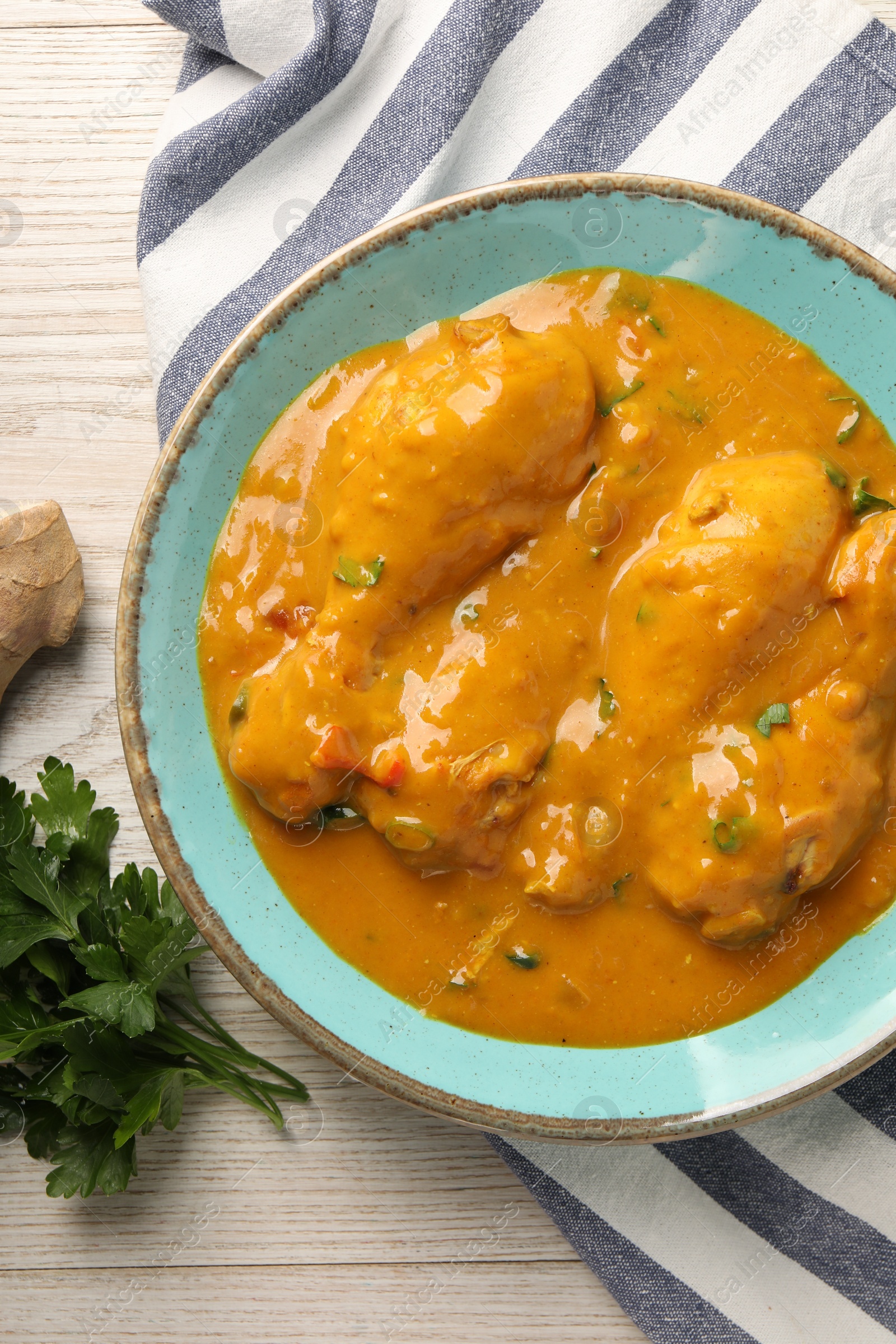 Photo of Tasty chicken curry, parsley and ginger on wooden table, flat lay