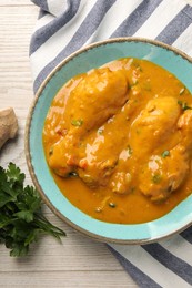 Photo of Tasty chicken curry, parsley and ginger on wooden table, flat lay