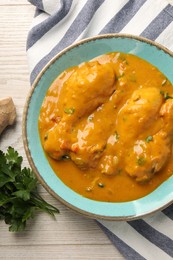 Tasty chicken curry, parsley and ginger on wooden table, flat lay