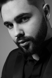 Photo of Handsome bearded man on grey background, closeup. Black and white effect