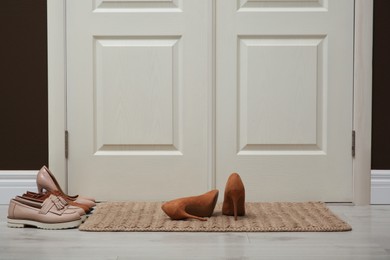 Photo of Stylish shoes and door mat in hall