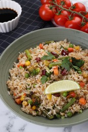 Photo of Tasty fried rice with vegetables served on white marble table, closeup