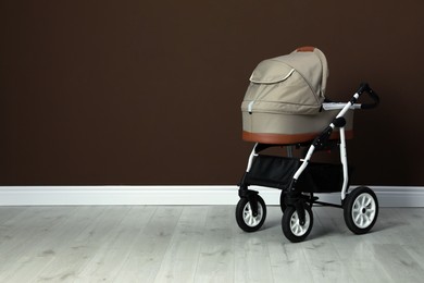 Baby carriage. Modern pram near brown wall, space for text
