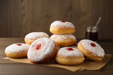 Photo of Many delicious donuts with jelly and powdered sugar on wooden table